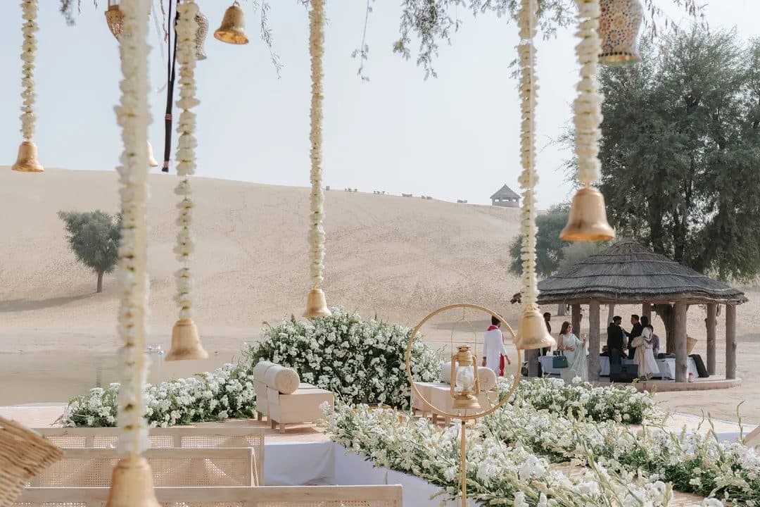 Floral mandap decor with hanging bells overlooking desert dunes