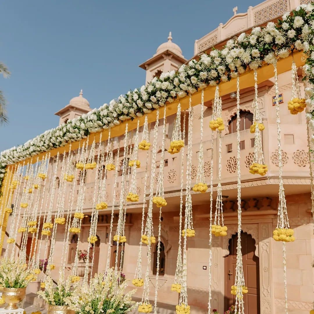 A palace facade draped in white and yellow floral garlands