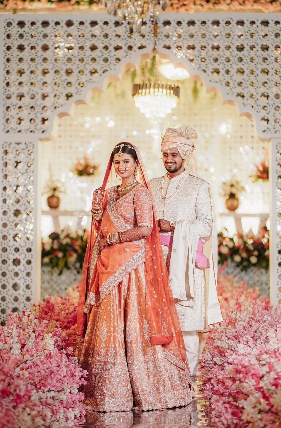 The bride and groom smiling under a floral mandap