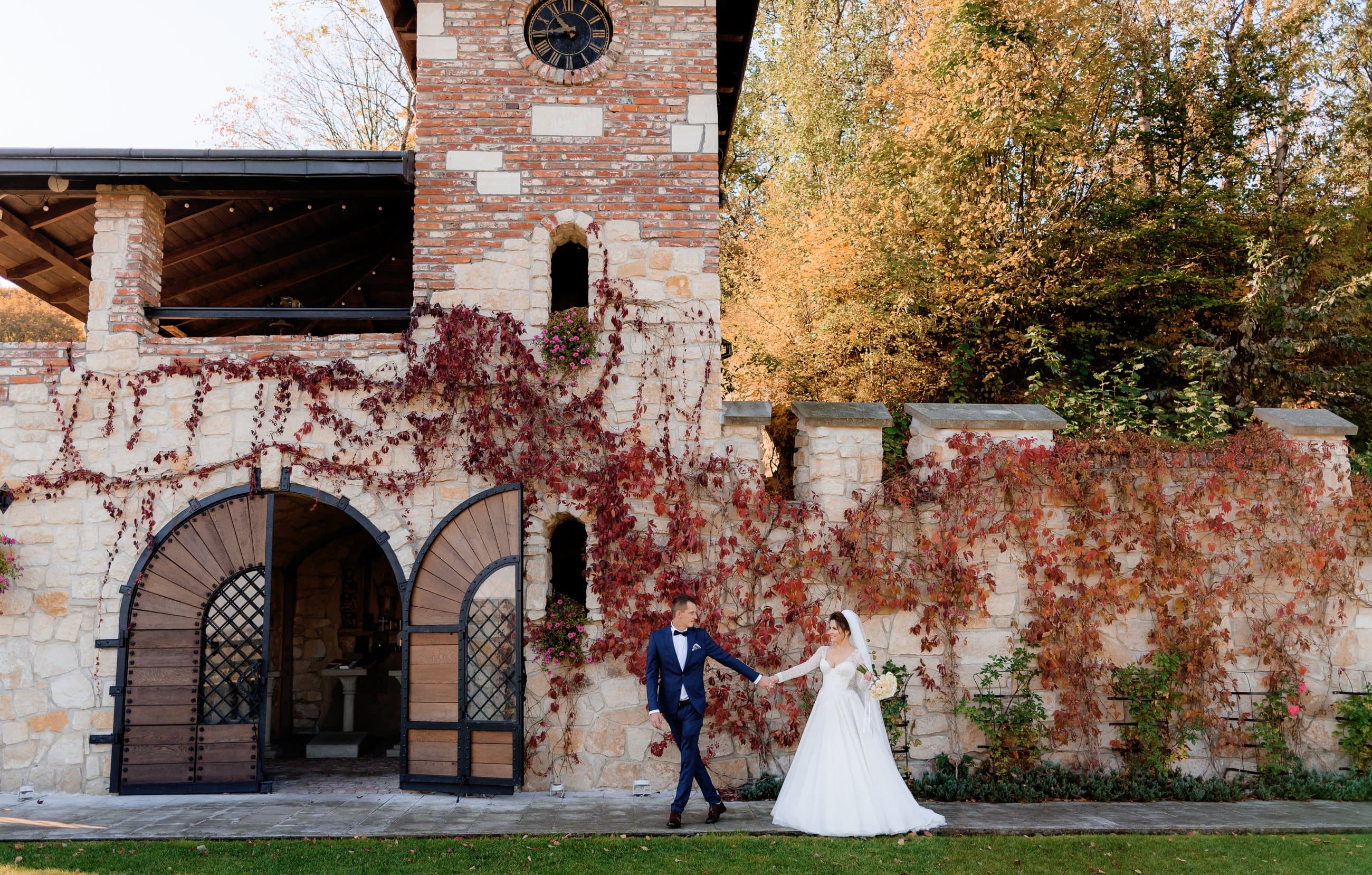 A bride and groom walking past an ivy-covered stone villa