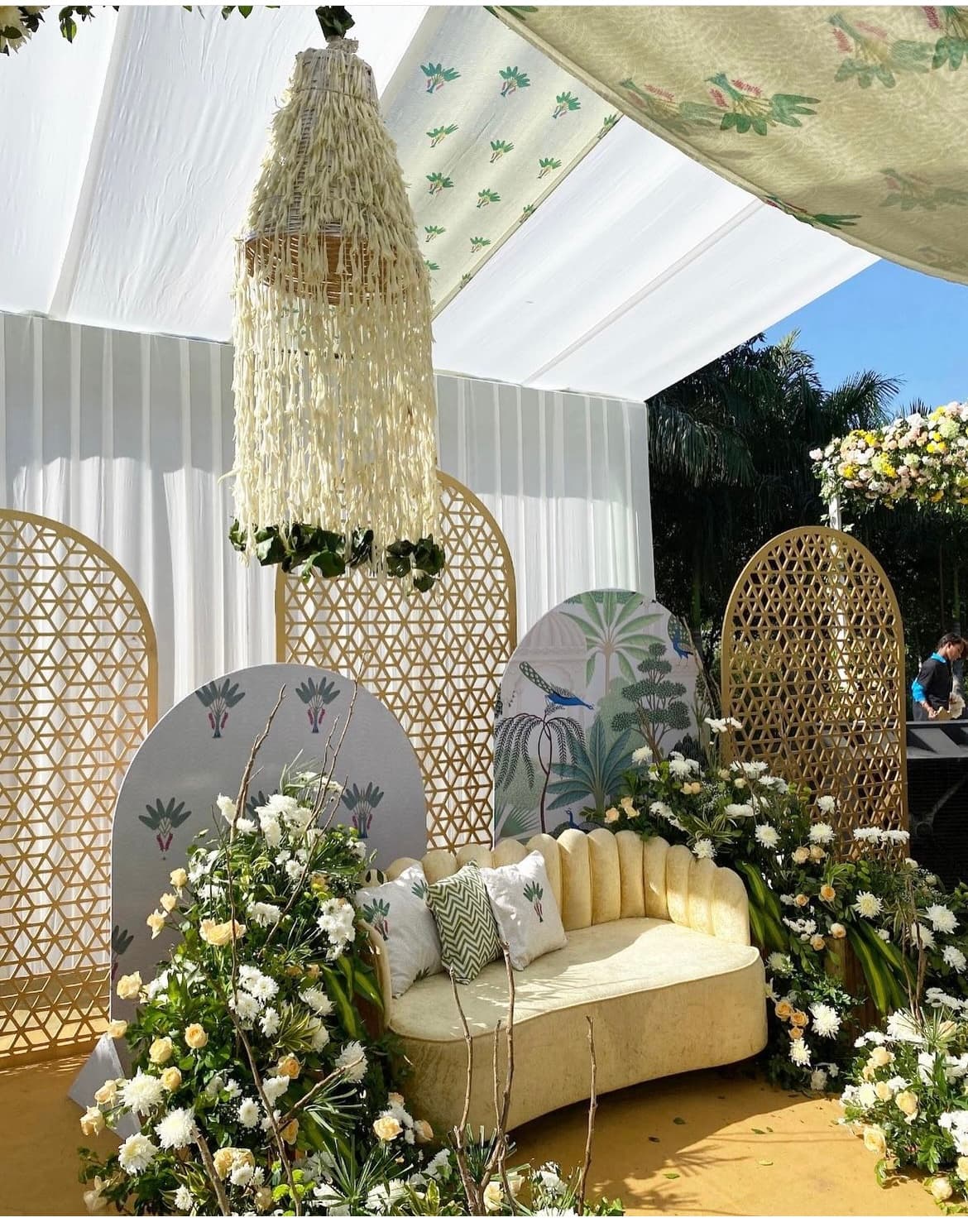 A floral lounge setup with cane screens beneath a draped tent
