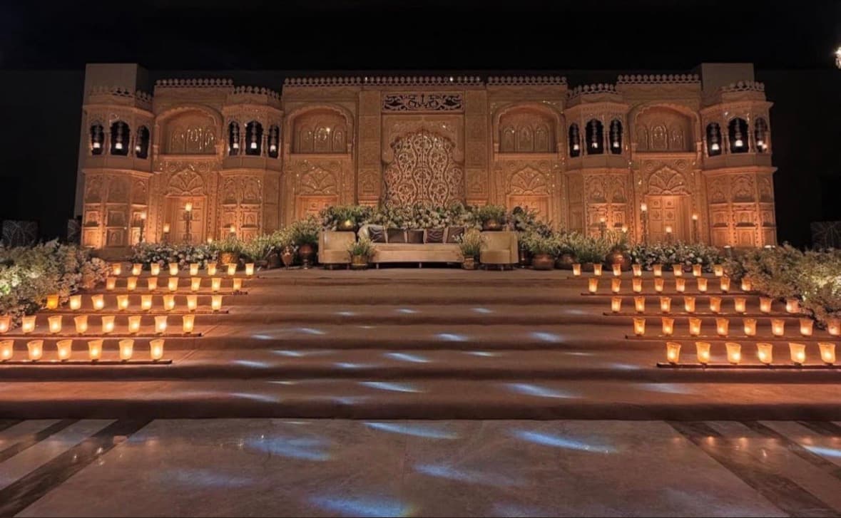 An illuminated palace facade with a candlelit aisle at night